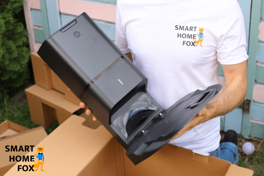 Die Absaugstation eines Roomba Saugroboters wird in den Händen gehalten